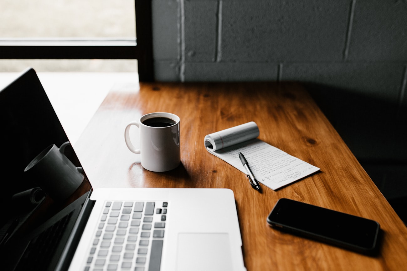 Espace de travail : ordinateur portable, carnet de notes et café sur un bureau en bois